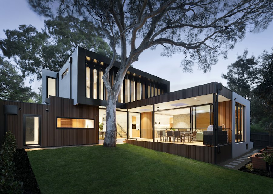 Modern home with large glass windows and a lawn